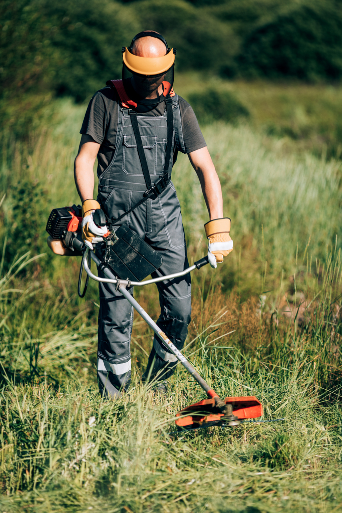 Esistono tante tipologie di decespugliatori per giardino: elettrici, a scoppio, a zaino, a batteria. Quello più adatto per il nostro giardino? Dipende dalle nostre esigenze. Nella foto, un giardiniere che adopera un decespugliatore.