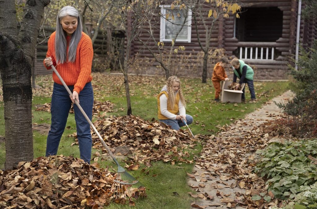 La cura del giardino in autunno è molto importante per preservare terreno e piante dall'arrivo dalla stagione invernale. Nella foto, bambini e persona adulta che spazzano via le foglie autunnali.