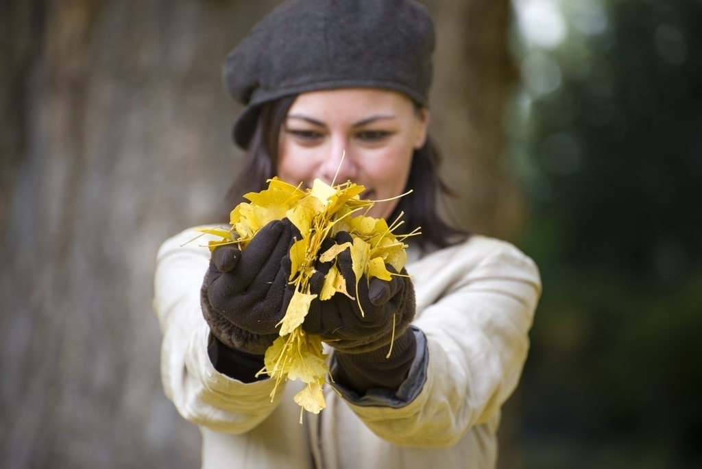 La cura del giardino in autunno è un'attività molto importante, dal momento che aiuta a proteggere le nostre piante dalle insidie dell'inverno. Nella foto, una donna che raccoglie delle foglie autunnali.